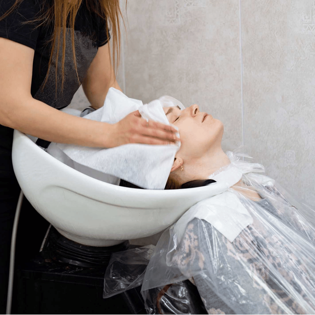 Peluquera secando el cabello de una clienta con toalla desechable SpunLace en Gran Canaria, ideal para higiene en salones de peluquería.