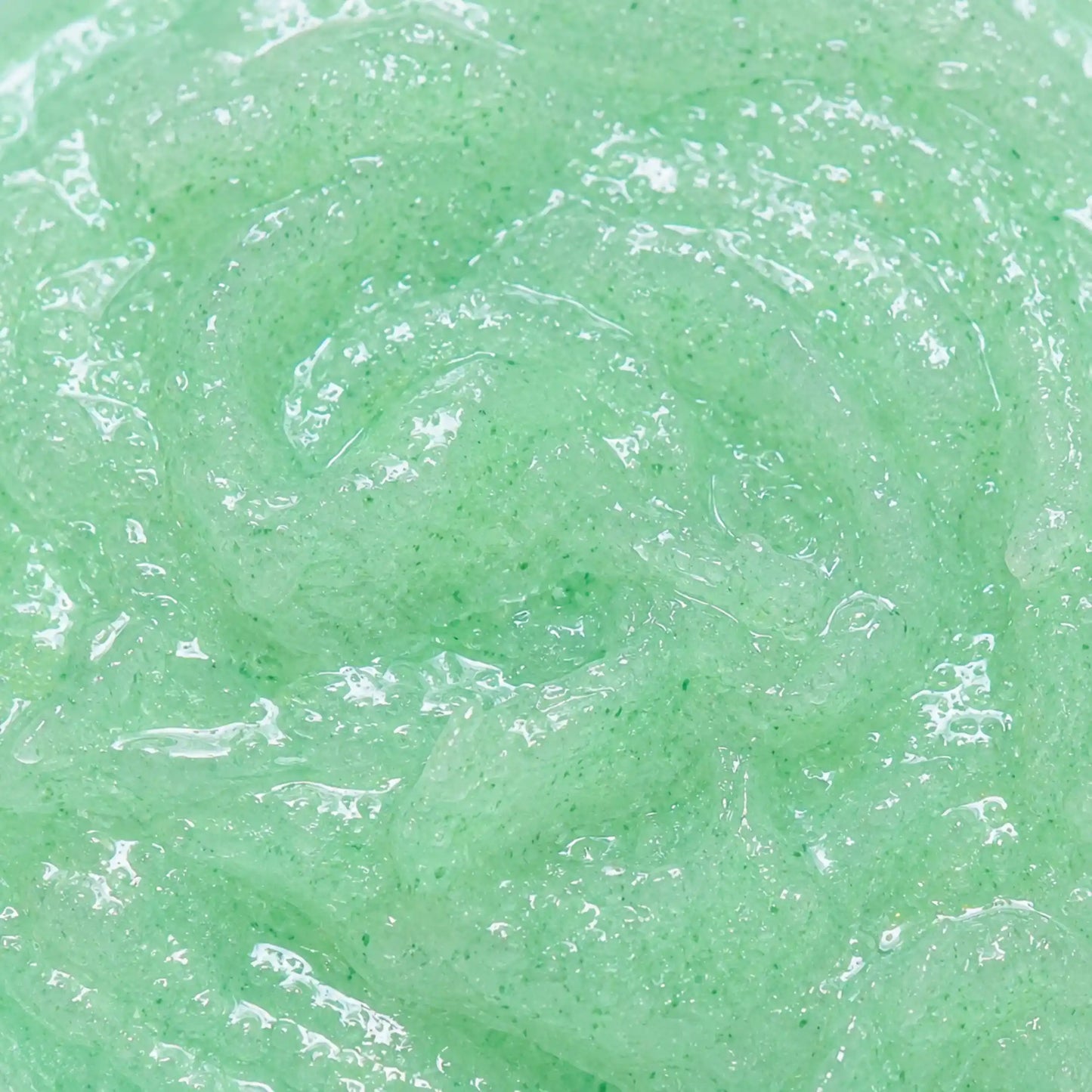 Vista cenital de la textura verdosa y transparente del Exfoliante Aloe Vera Scrub Kefus, mostrando al detalle sus gránulos exfoliantes