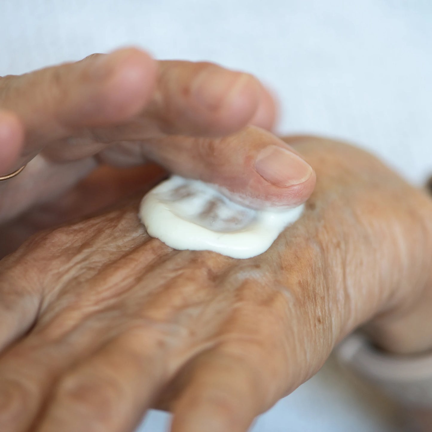 Aplicación de Body Milk Corporal & Hidratante S’Nonas en la mano de una mujer mayor para el cuidado diario de la piel en Gran Canaria