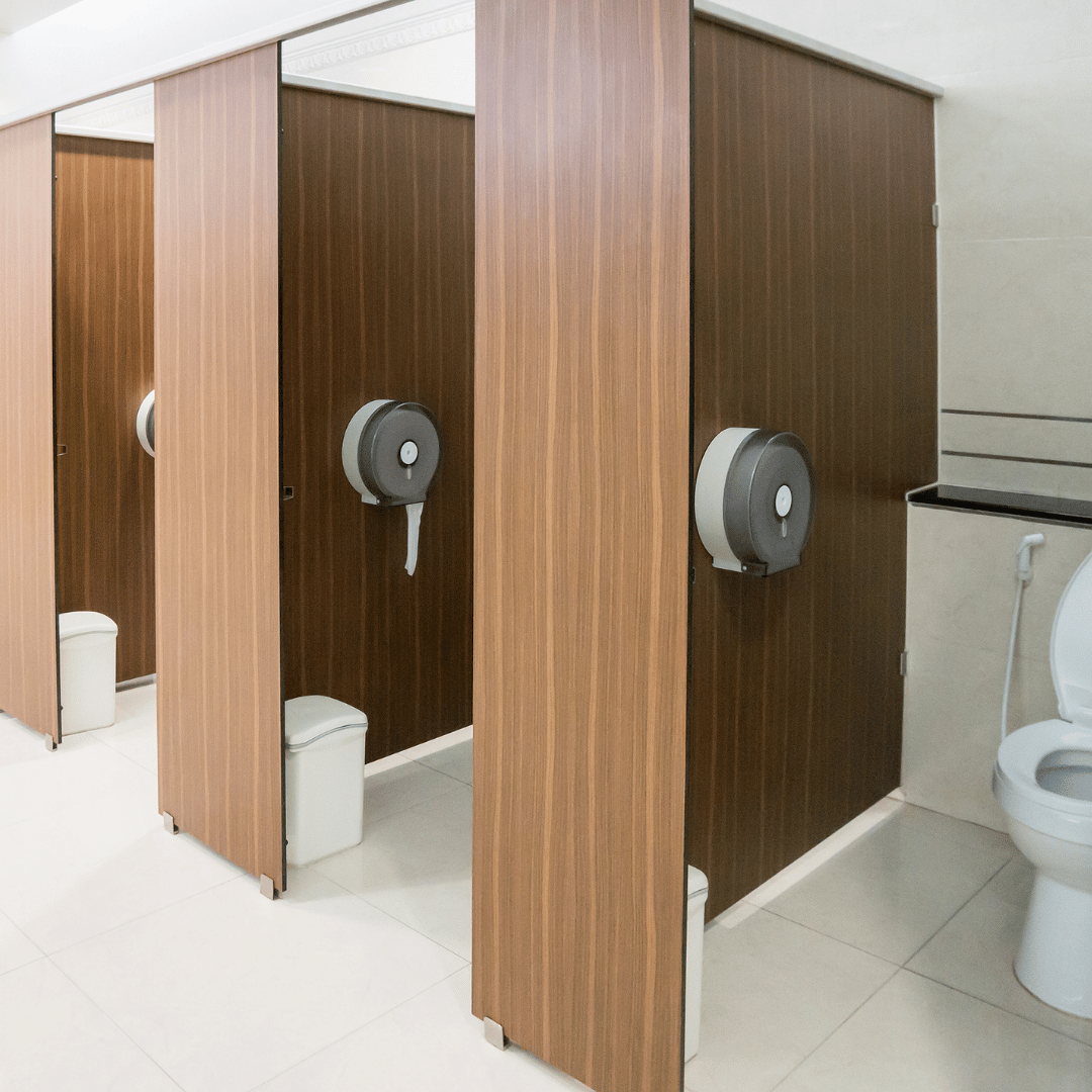 Baño público equipado con dispensadores de papel higiénico industrial de celulosa.