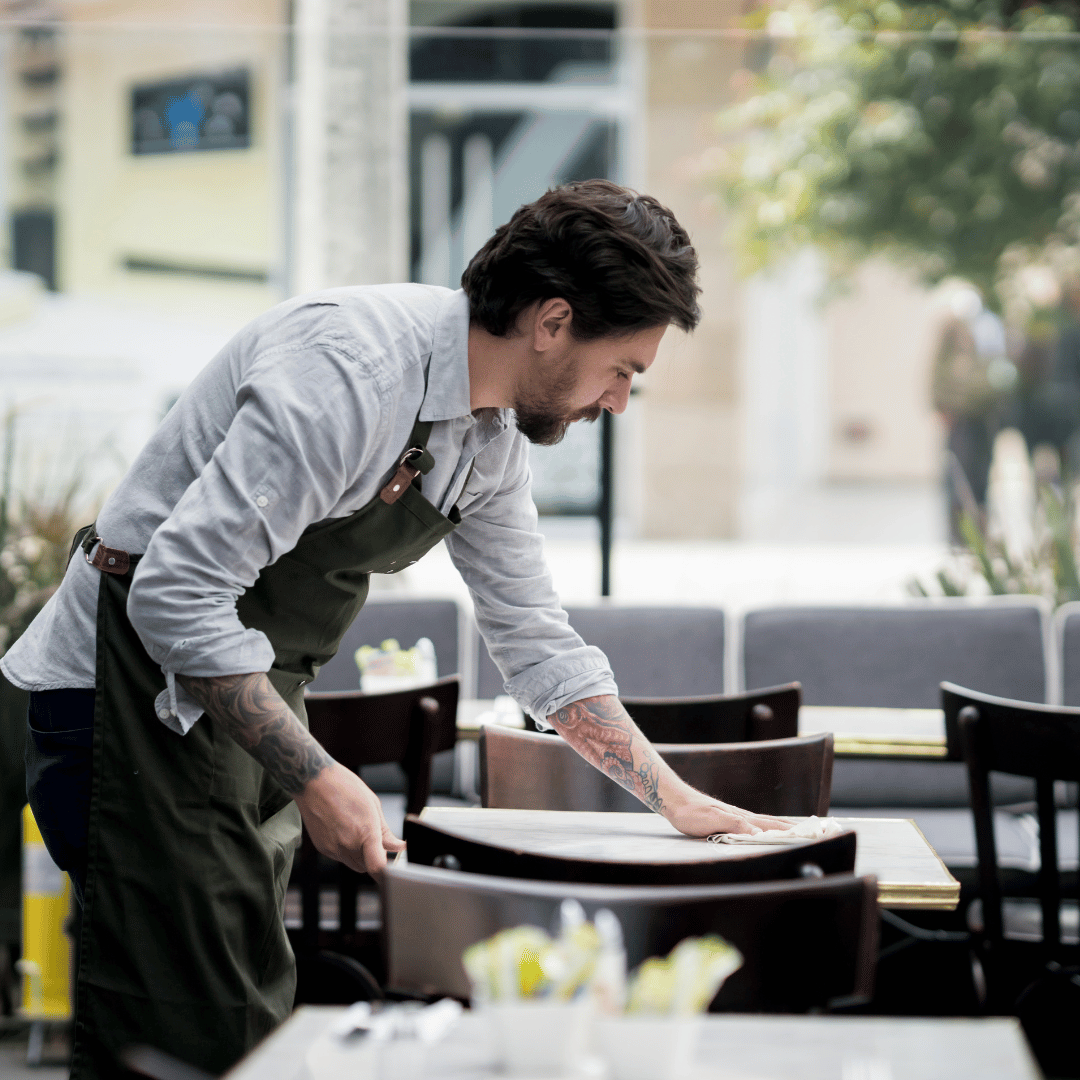 Camarero en terraza utilizando papel secamanos ecológico 800GR para limpieza rápida e higiénica en cafeterías y restaurantes de Gran Canaria.