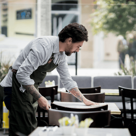 Camarero en terraza utilizando papel secamanos ecológico 800GR para limpieza rápida e higiénica en cafeterías y restaurantes de Gran Canaria.