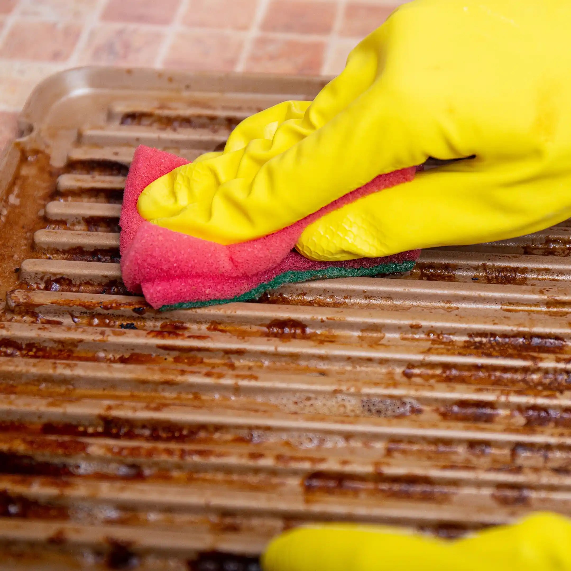 Desengrasante profesional para parrillas y planchas en Gran Canaria, eliminando grasa con estropajo sobre superficie de cocina.