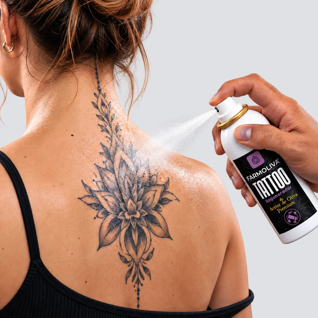 Aplicación de Farmoliva Tattoo Regenerador Spray sobre un tatuaje en la espalda de una chica para el cuidado, hidratación y protección de la piel tatuada.