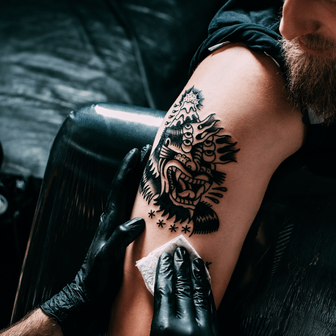 Tatuador usando guantes de nitrilo negro en estudio de tattoo en Gran Canaria, garantizando higiene y precisión.