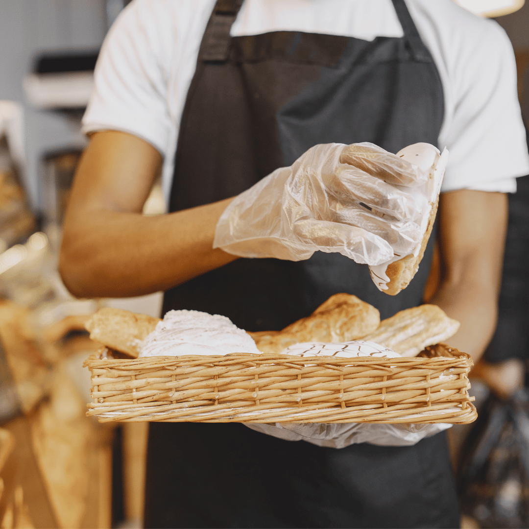 Empleado en frutería usando guantes de polietileno transparente para manipular frutas y verduras con seguridad e higiene en Gran Canaria.
