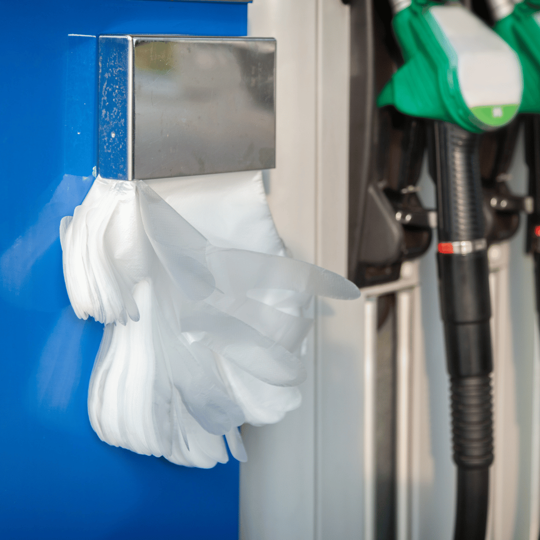 Persona usando guantes de polietileno transparente en gasolinera en Gran Canaria para manipular surtidores, efectivo y tarjetas con higiene.