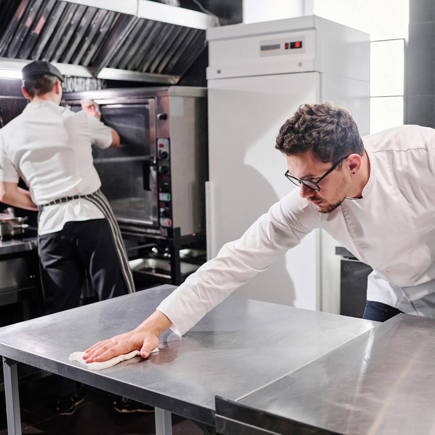 Limpieza profesional de superficies de cocina en Gran Canaria, con mesa de acero inoxidable y horno tratados con productos de limpieza.