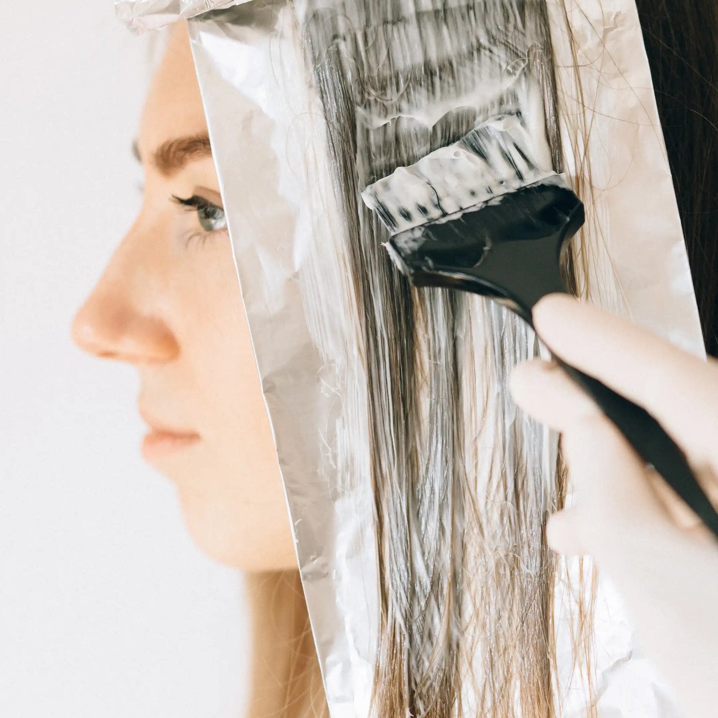 Profesional aplicando producto de coloración sobre un mechón de cabello colocado en papel de aluminio en Gran Canaria