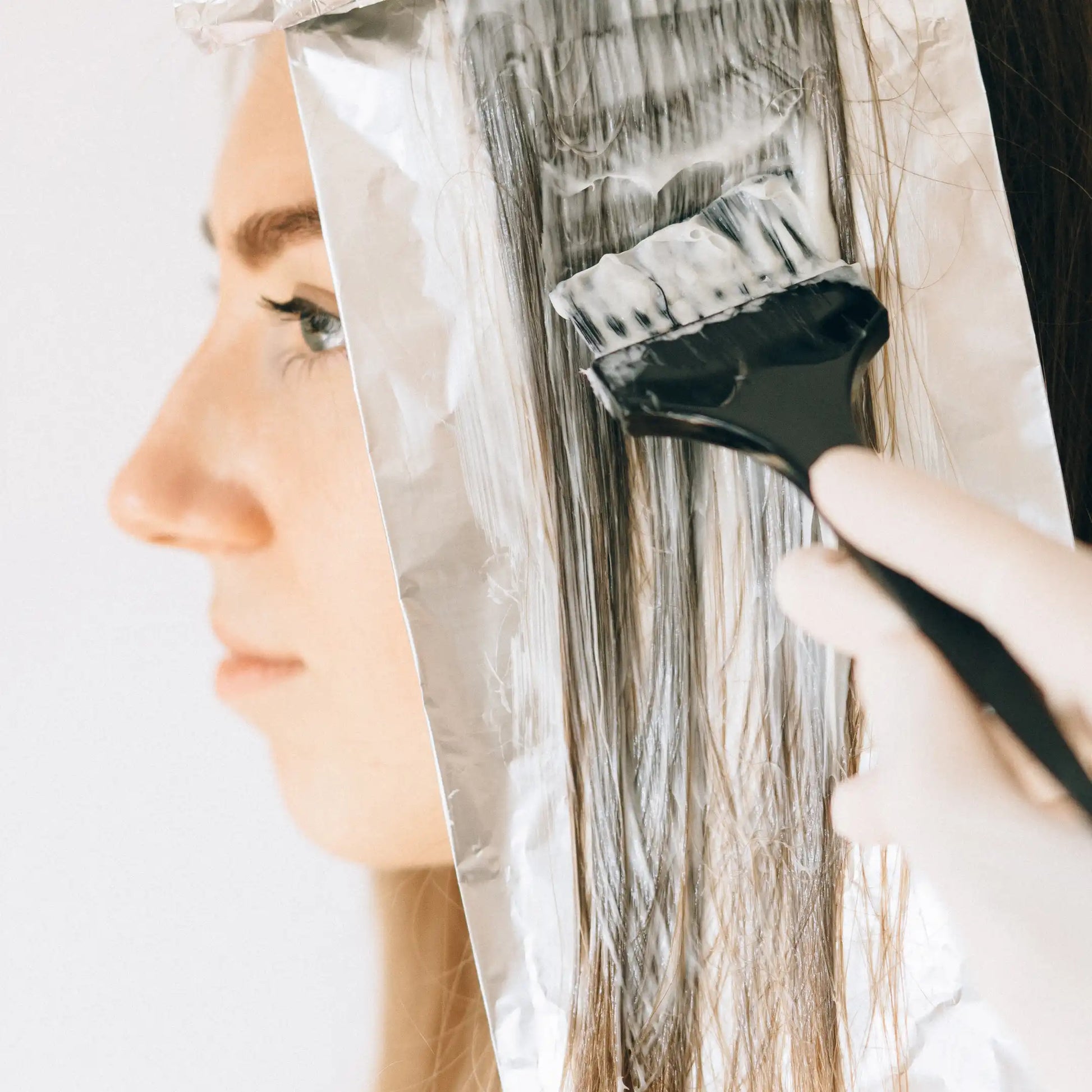 Profesional aplicando producto de coloración sobre un mechón de cabello colocado en papel de aluminio en Gran Canaria