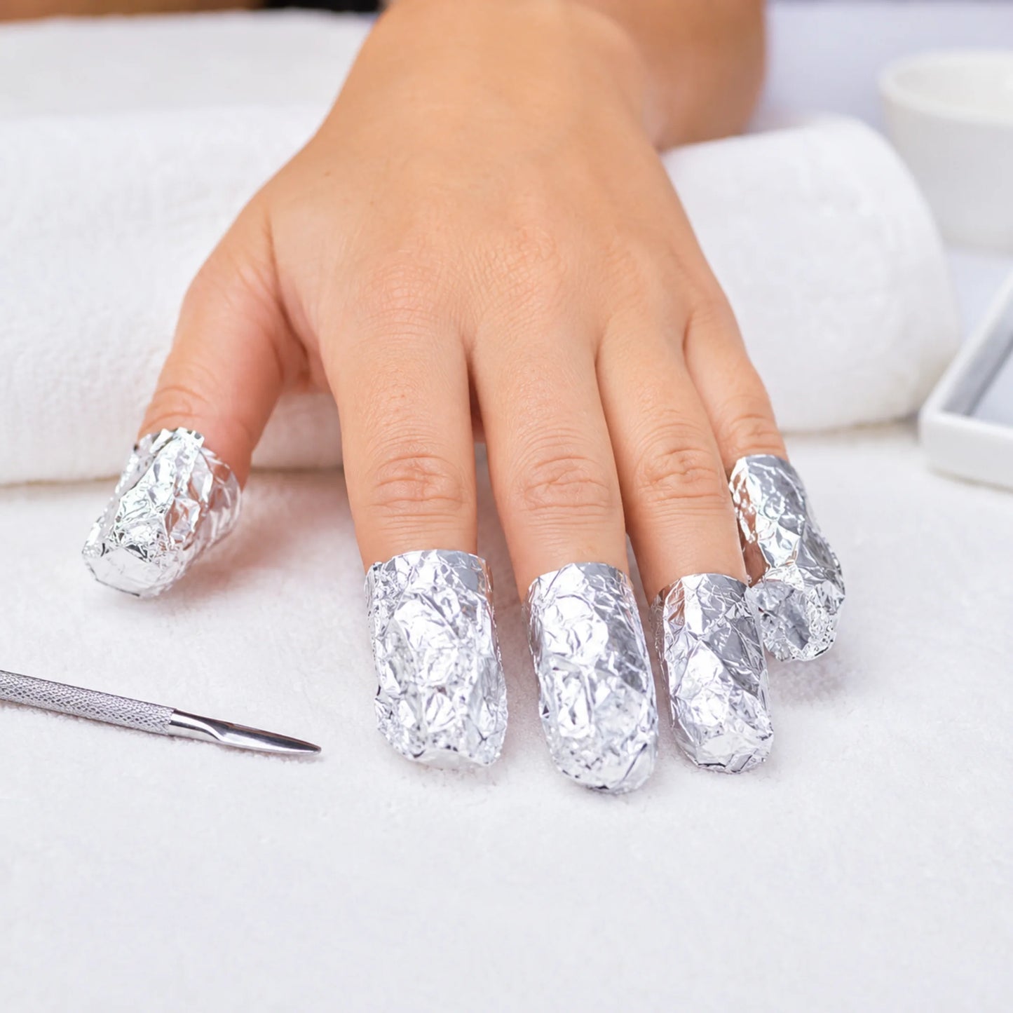 Manos de una clienta con los dedos envueltos en papel de aluminio durante un servicio de manicura en Gran Canaria