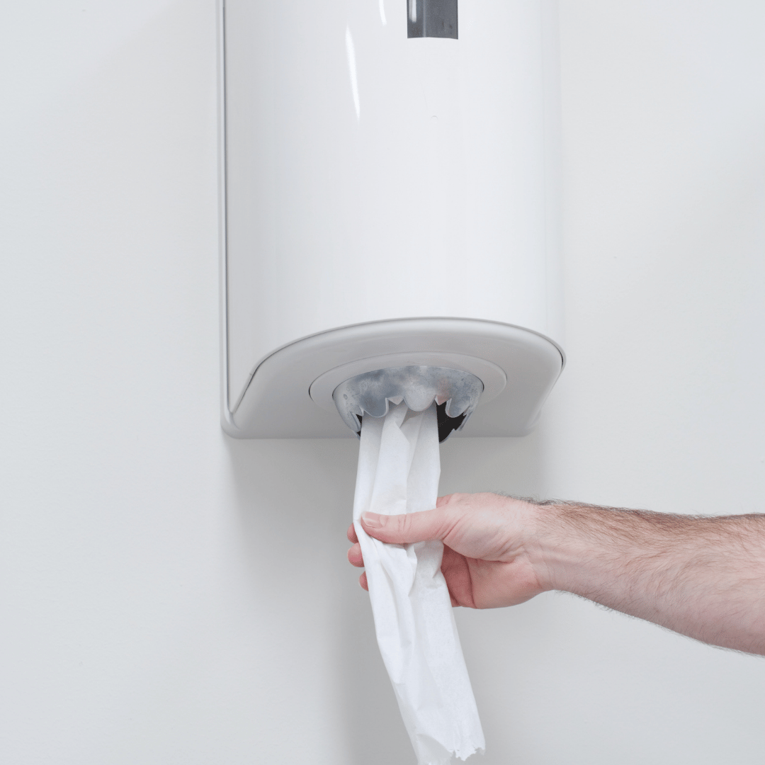 Persona tirando del papel desde un dispensador Mini Cheminé, ideal para higiene eficiente en entornos profesionales o industriales en Gran Canaria.