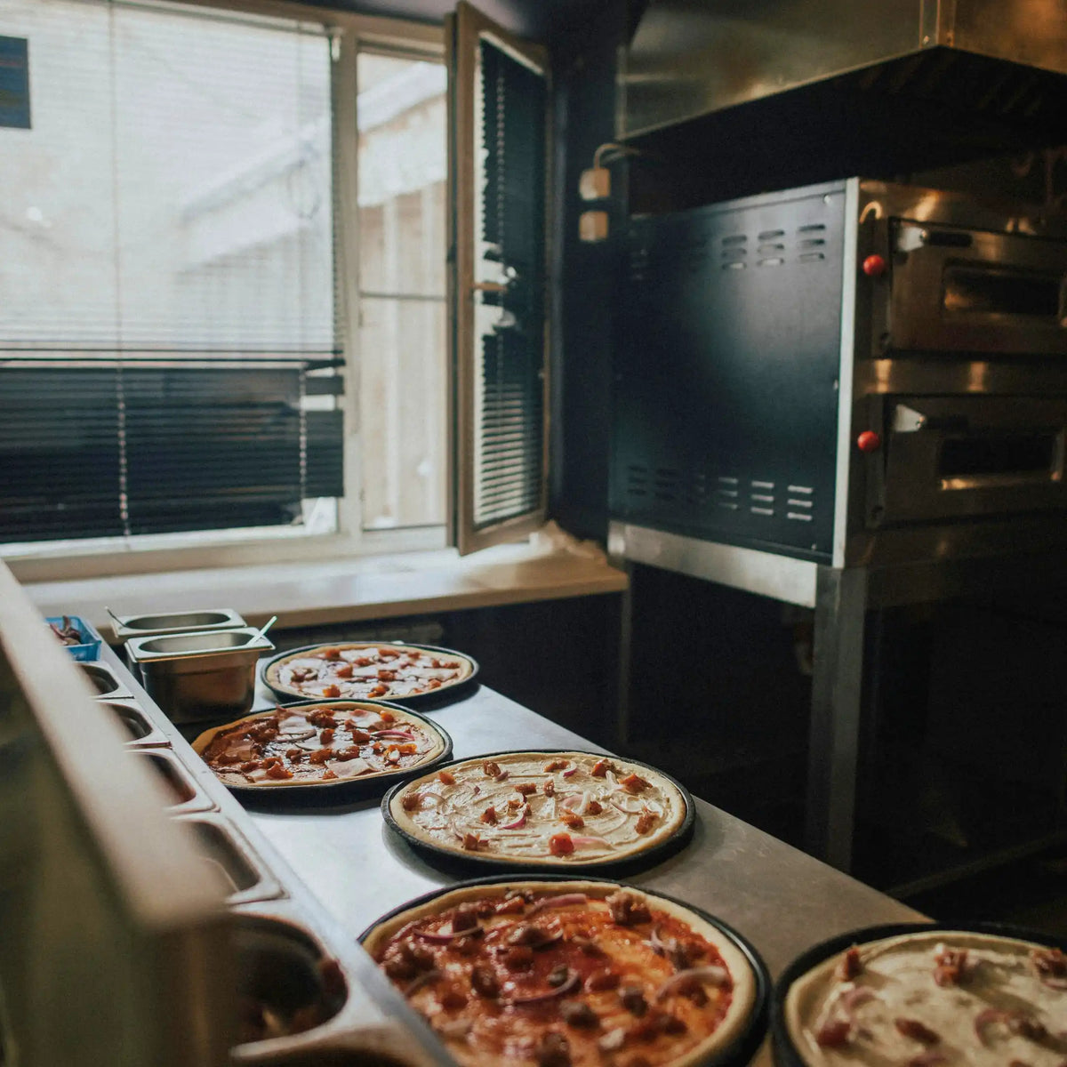 Pizzas recién preparadas y listas para hornear en una pizzería de Gran Canaria.