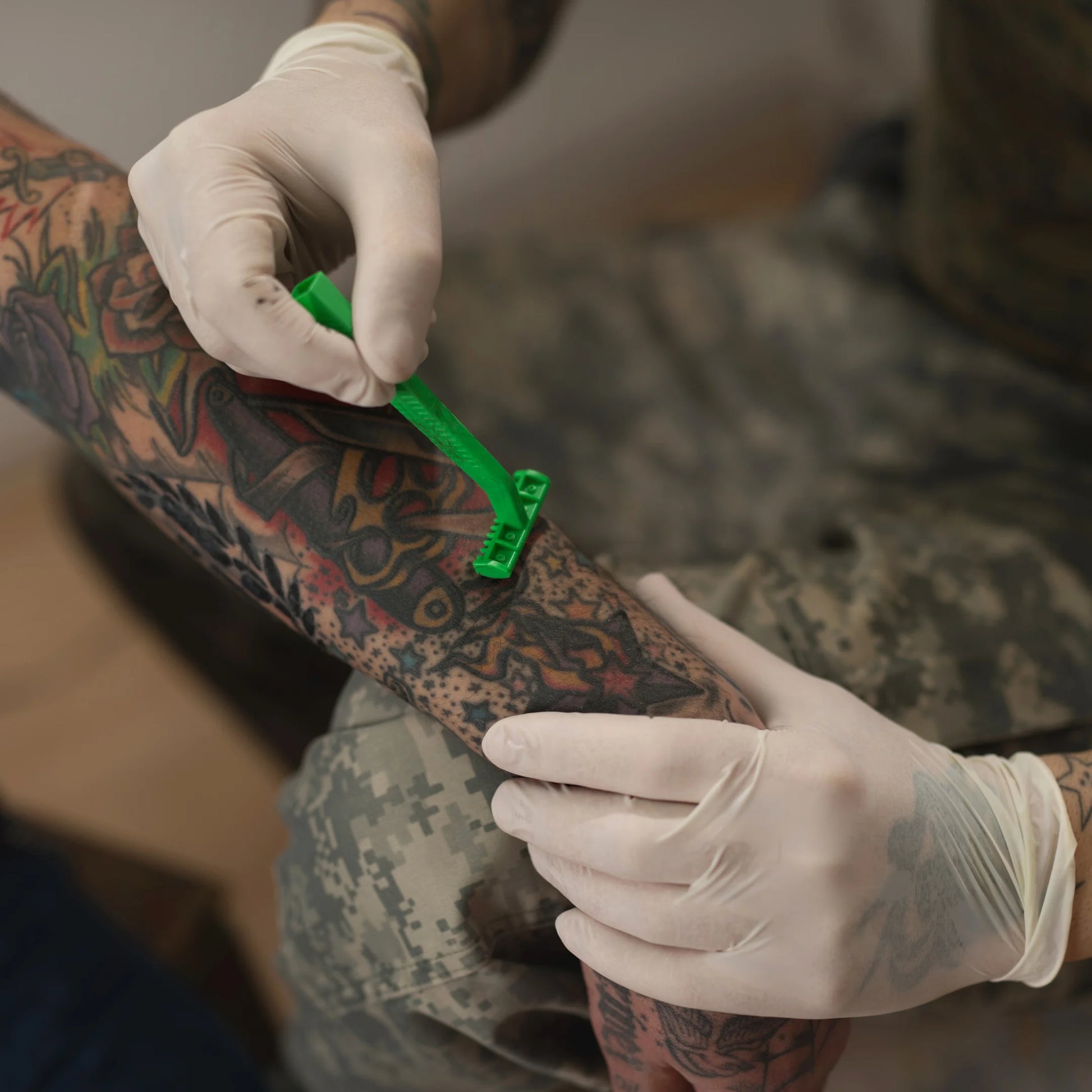 Tatuador retirando el vello de la piel de un cliente con una rasuradora desechable verde de dos hojas antes de realizar el tatuaje en Gran Canaria.