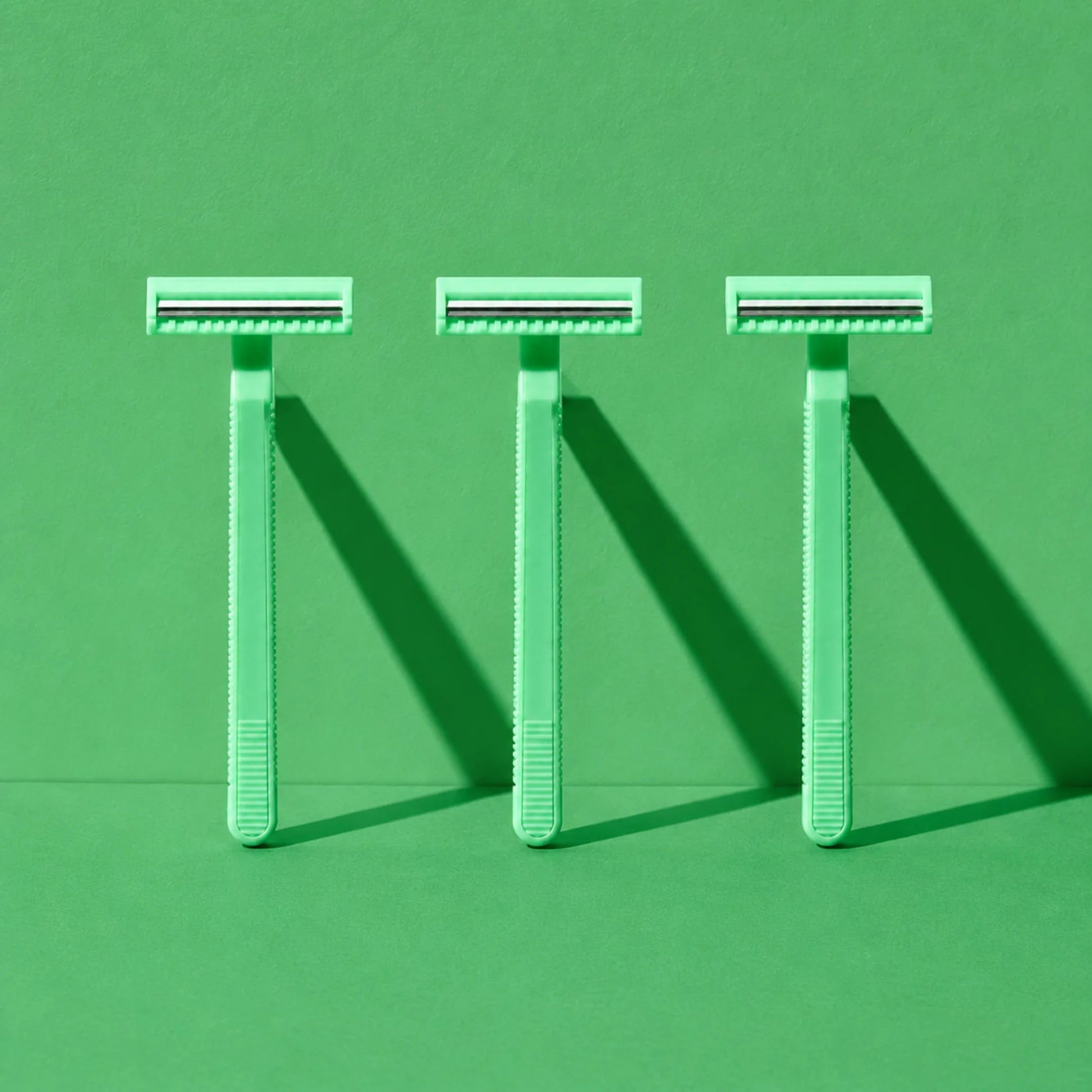 Tres Rasuradoras Desechables de 2 Hojas verdes en una composición estética de estudio
