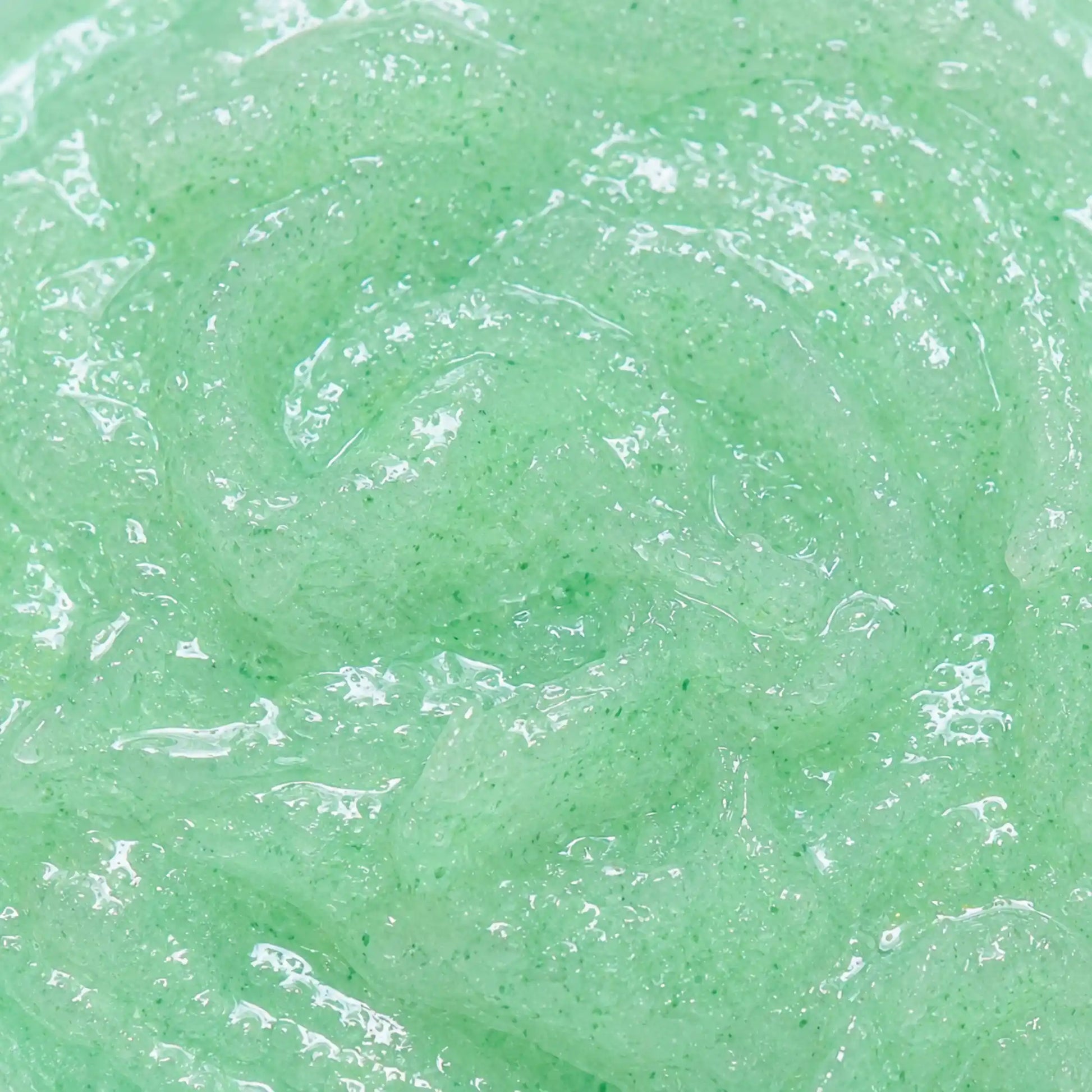 Vista cenital de la textura verdosa y transparente del Exfoliante Aloe Vera Scrub Kefus, mostrando al detalle sus gránulos exfoliantes